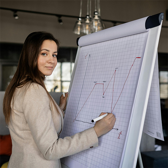 A woman engaged in writing on a whiteboard, showcasing her thoughts and concepts in a professional setting.