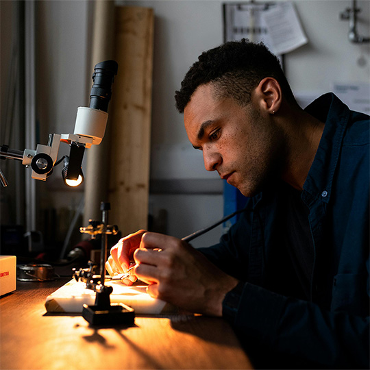 A man engaged in a project, showcasing craftsmanship in a workshop filled with tools and workbenches.