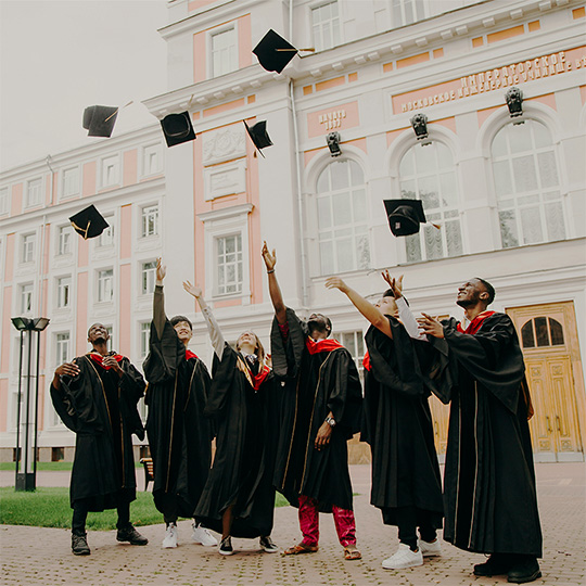 Graduates celebrate their success by throwing their caps high into the air, capturing a moment of joy and accomplishment.