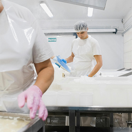 A man wearing a clean room style suit is examining materials in a pharmaceutical factory.