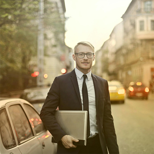 A man in a suit and glasses is showcasing a laptop, illustrating a combination of professionalism and contemporary technology.