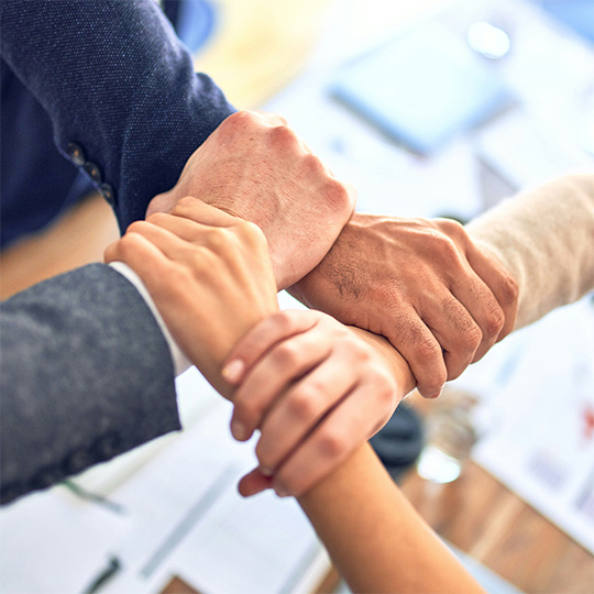 A team of business individuals holding hands, representing cooperation and collective effort in the workplace.
