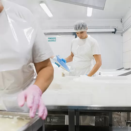 A man wearing a clean room style suit is examining materials in a pharmaceutical factory.